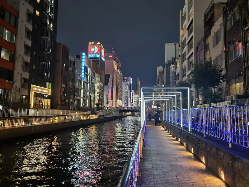 Lối đi bộ sáng đèn và các tòa nhà rực rỡ neon dọc kênh Dotonbori về đêm ở Osaka.