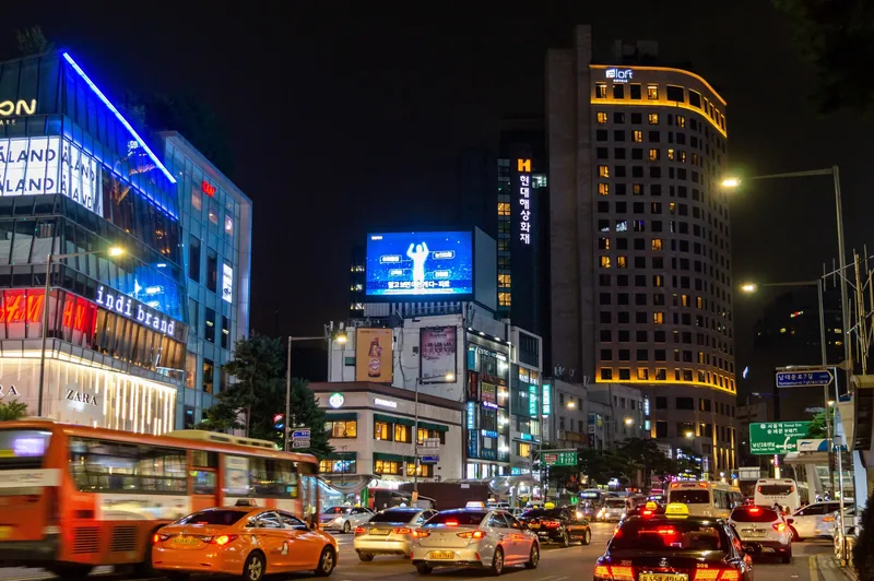Giao thông nhộn nhịp và các bảng quảng cáo rực sáng trên con phố ở Seoul vào ban đêm.