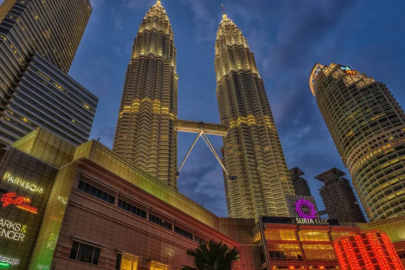 Tháp Petronas rực sáng phía trên trung tâm mua sắm Suria KLCC ở Kuala Lumpur lúc chạng vạng.