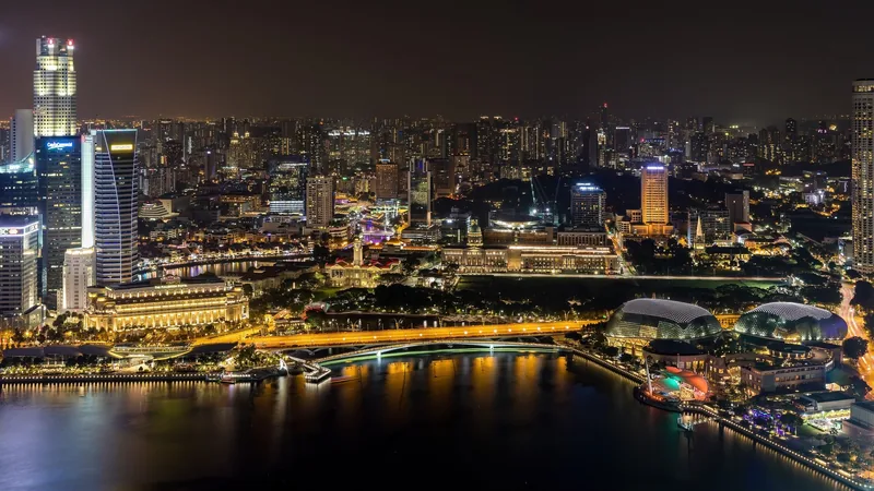 Đường chân trời Singapore rực sáng ánh đèn bên dòng sông về đêm, nhìn từ trên cao.