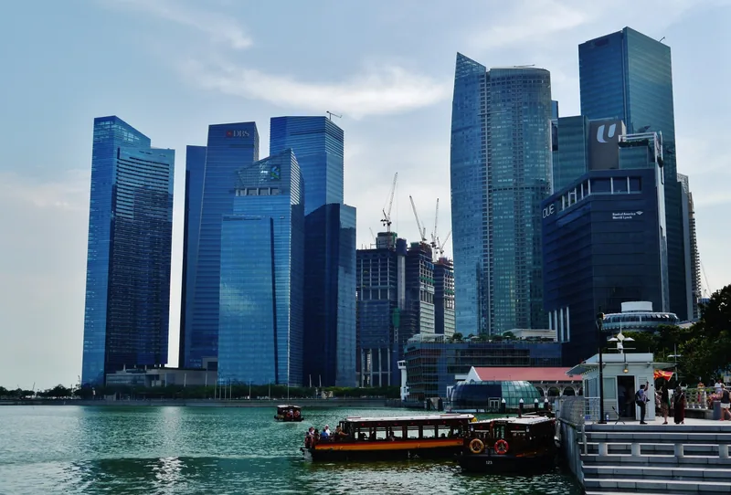 Các tòa nhà chọc trời trong khu tài chính Singapore vươn cao bên Vịnh Marina với thuyền du lịch đậu ven bờ.