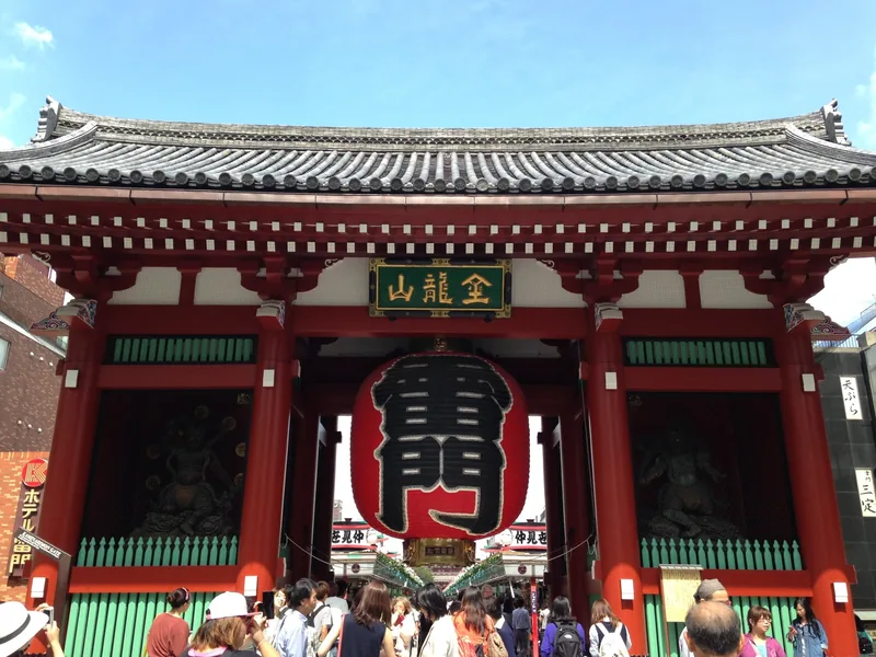 Du khách tụ tập dưới chiếc đèn lồng đỏ lớn và mái ngói của cổng Kaminarimon ở Tokyo
