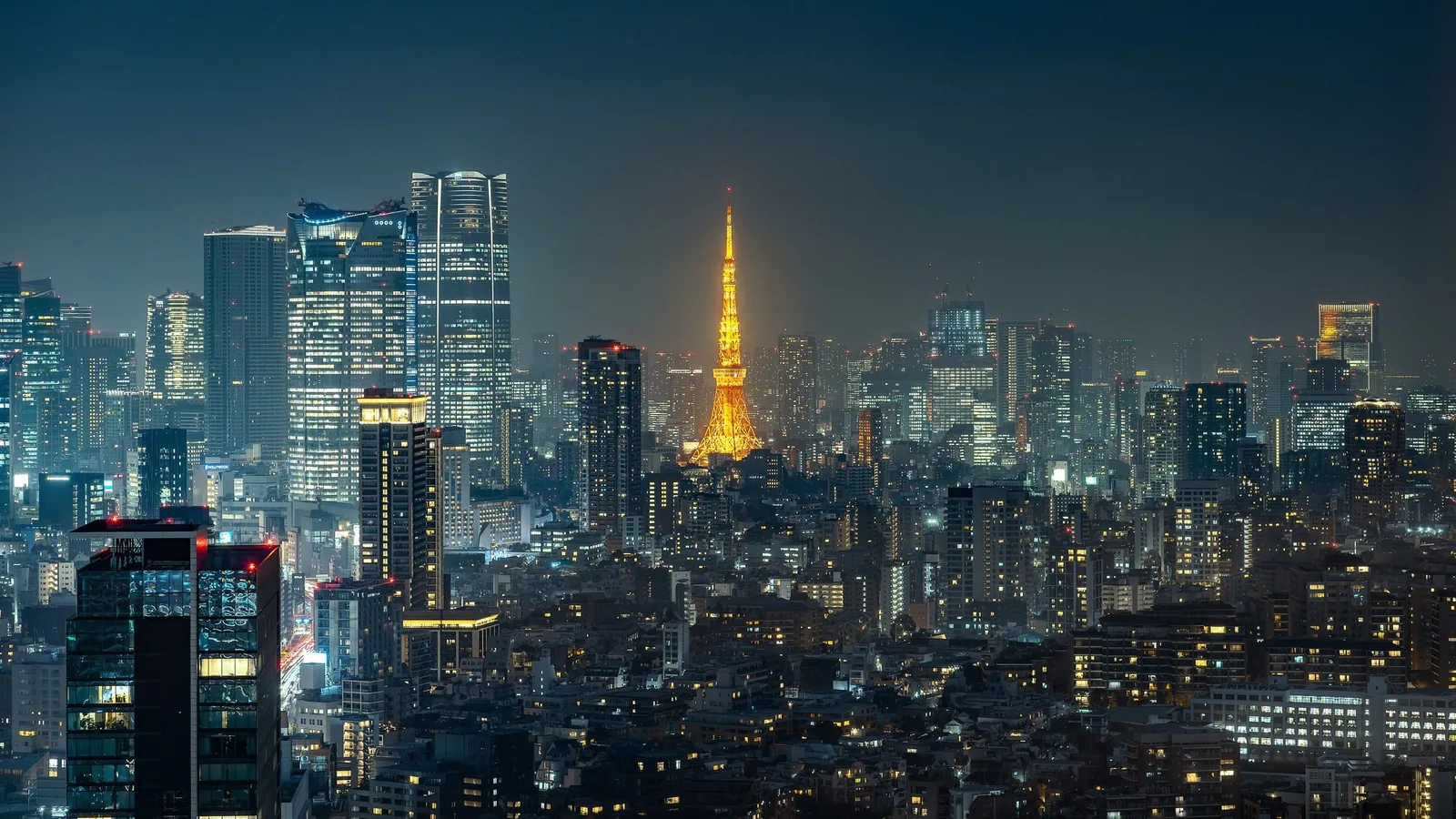Tháp Tokyo rực sáng màu cam giữa khung cảnh các tòa nhà cao tầng lấp lánh ánh đèn về đêm ở Minato.