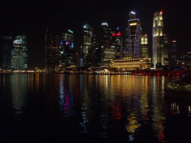 Các tòa cao tầng rực sáng của Singapore phản chiếu trên mặt nước Vịnh Marina về đêm.